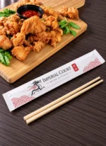 Bamboo chopsticks beside a custom printed paper chopstick sleeve – custom printed packaging by Texas Food Pack