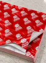 Stack of custom printed red insulated foil sandwich wrap sheets with silver foil lining – custom printed packaging by Texas Food Pack